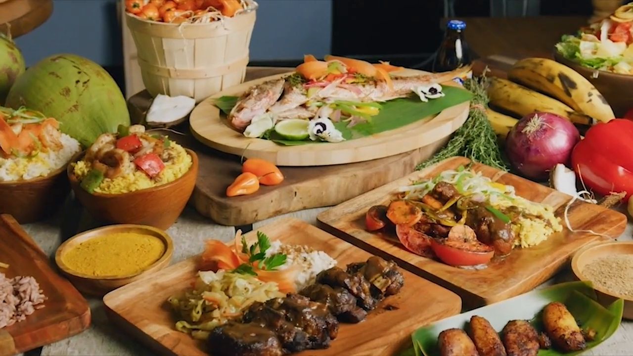 A Caribbean spread on wooden boards: whole fish, jerk, plantains and curry